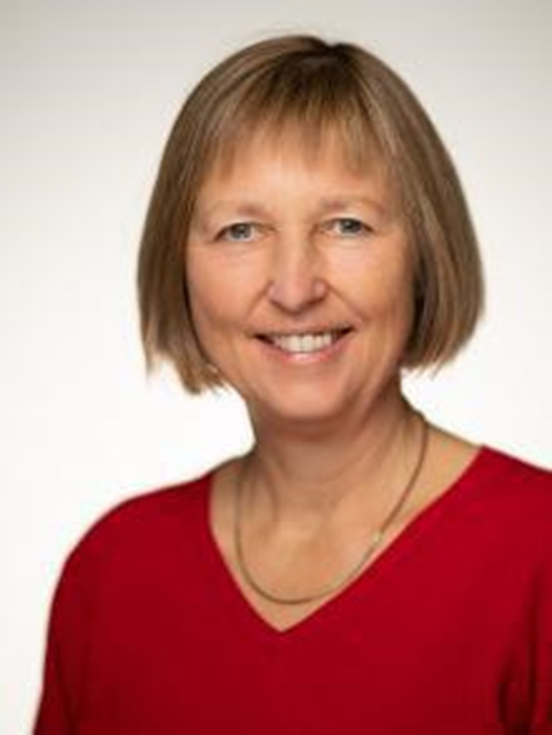 Dame lacht in die Kamera und trägt ein rotes Oberteil.